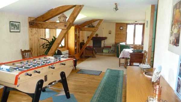 Salon mansardé avec baby-foot et charpente en bois apparente