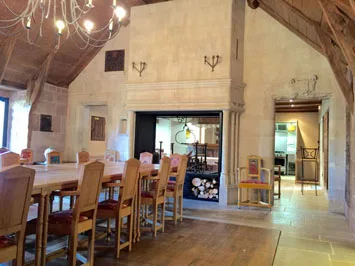 Salle à manger voûtée avec cheminée en pierre et grand lustre en fer forgé