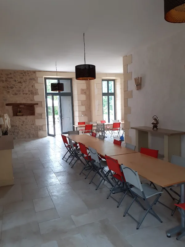 Grande salle de réception voûtée avec cheminée en pierre et longues tables dressées