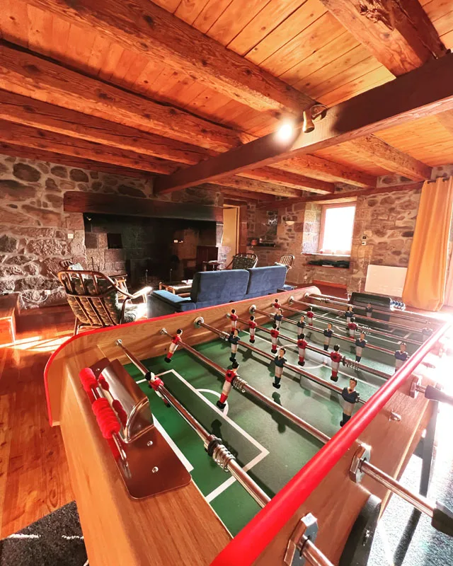 Salle de jeux mansardée avec baby-foot sous charpente en bois apparente