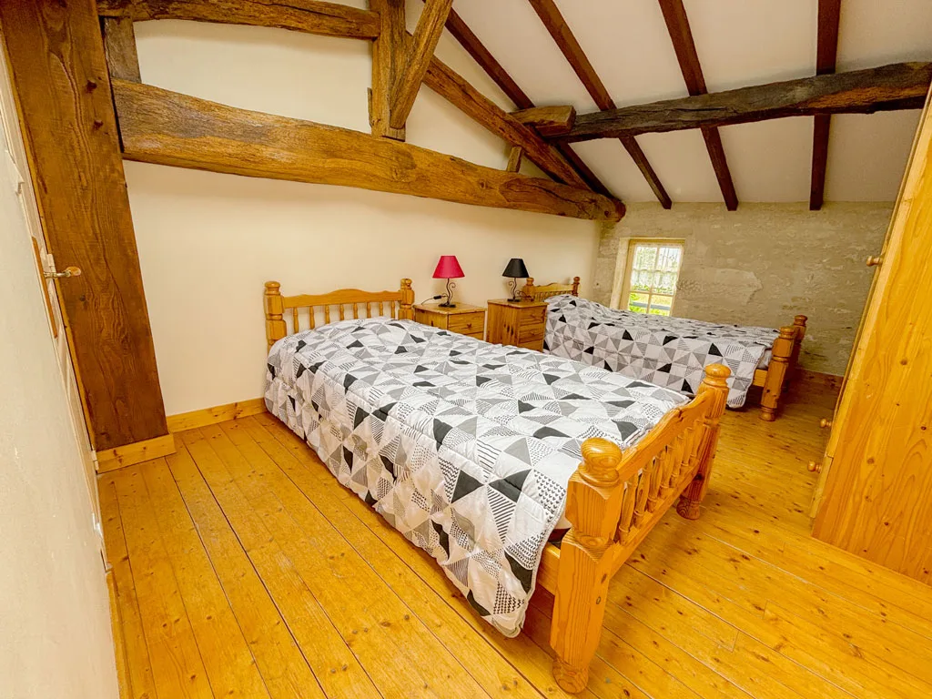 Chambre sous combles avec lit double orange et charpente en bois apparente