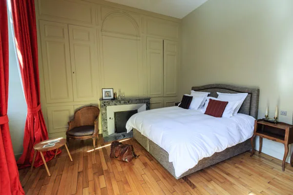 Chambre avec cheminée en marbre et rideaux rouges
