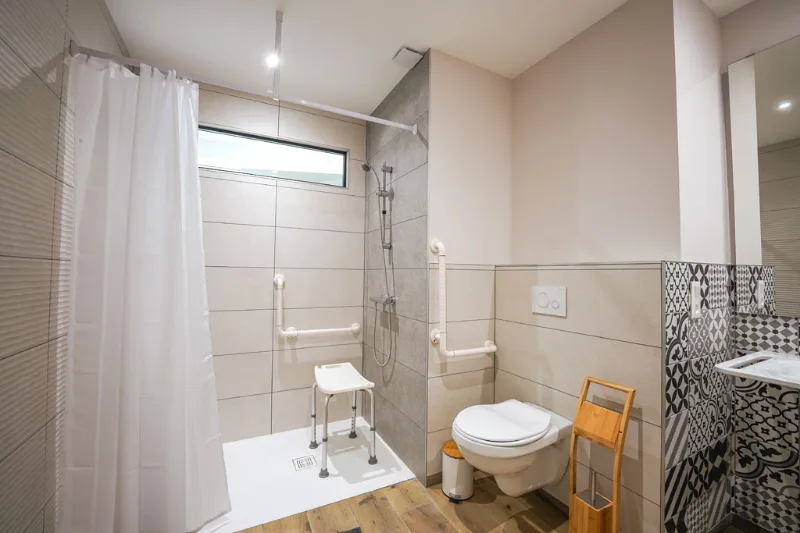 Salle de bain accessible PMR avec douche à l'italienne et barres d'appui