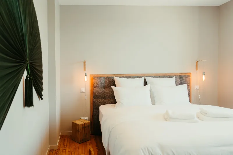Chambre avec tête de lit en bois, décoration en feuille de palmier et éclairages tamisés