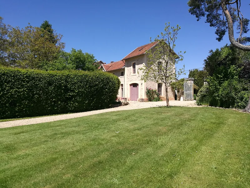 Vue extérieure de la longère avec pelouse, allée gravillonnée et grand parc arboré