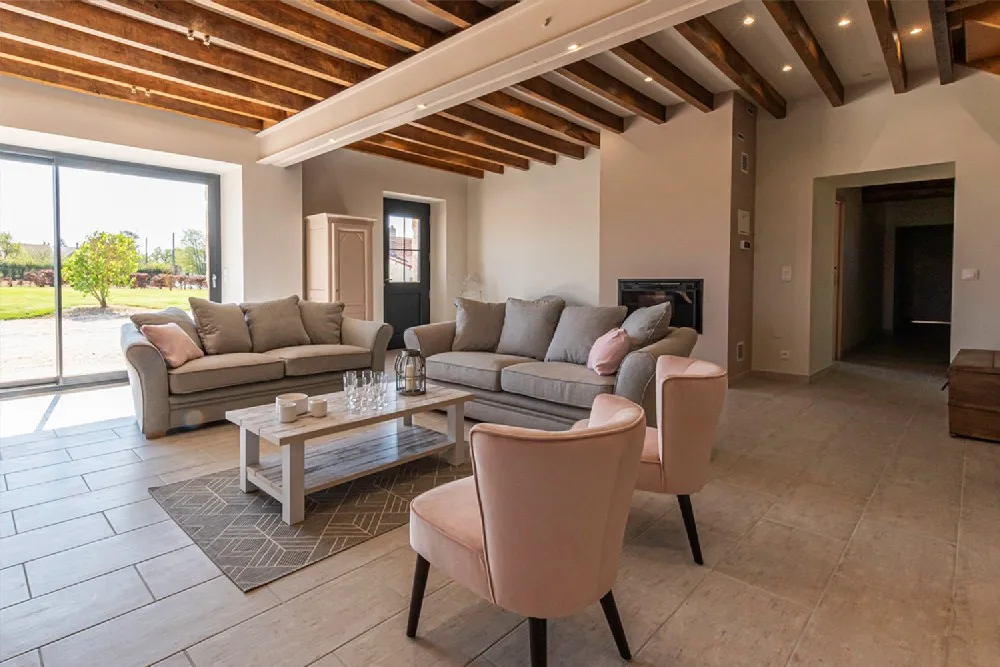 Salon cosy avec canapés et fauteuils sous poutres apparentes