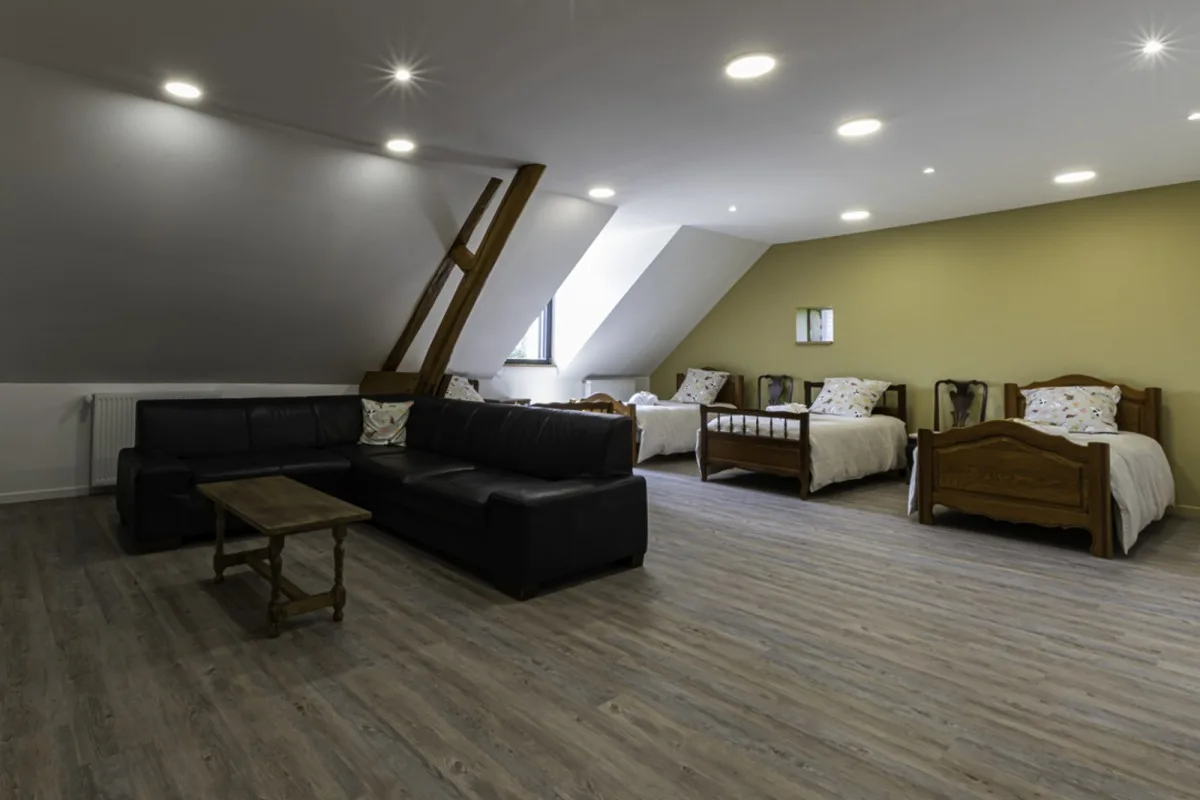 Salon avec piano droit sous charpente en bois, second espace de vie à l'étage