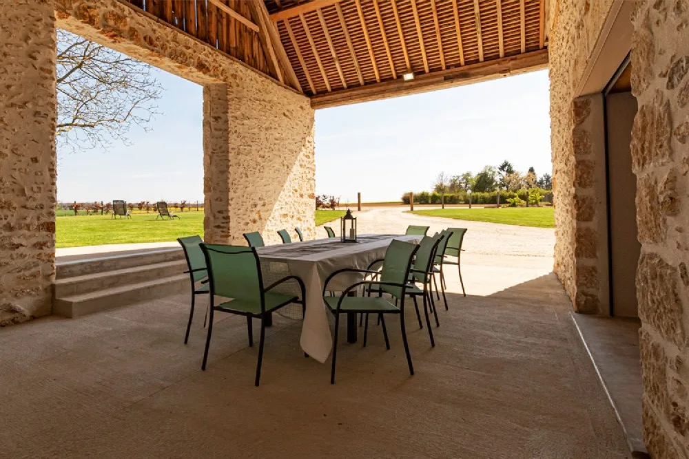 Terrasse couverte en pierre avec grande table pour repas en extérieur