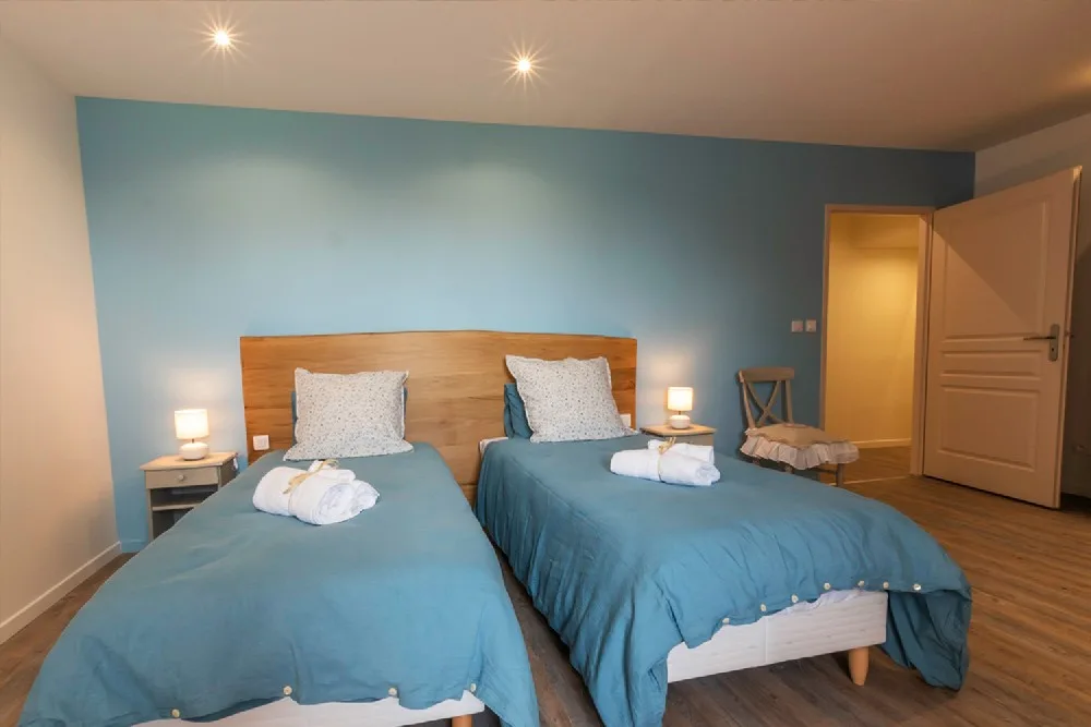 Chambre avec deux lits simples jumelables et tête de lit bleue