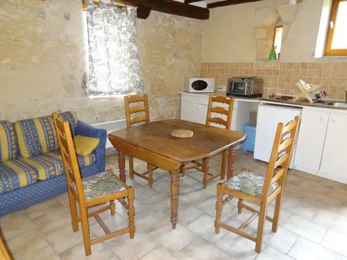 Coin repas avec canapé, table en bois et cinq chaises près de la cuisine équipée