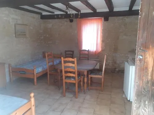 Séjour avec poutres apparentes, table en bois pour six convives et rideaux orange