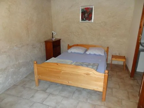 Chambre double avec lit en bois clair, chevets et sol carrelé aux tons beiges