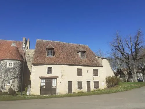 Bâtiment du gîte en pierre avec toiture d'ardoise, lucarnes à volets et façade blanche
