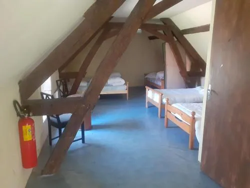 Dortoir aménagé sous combles avec charpente en bois apparente et lits simples