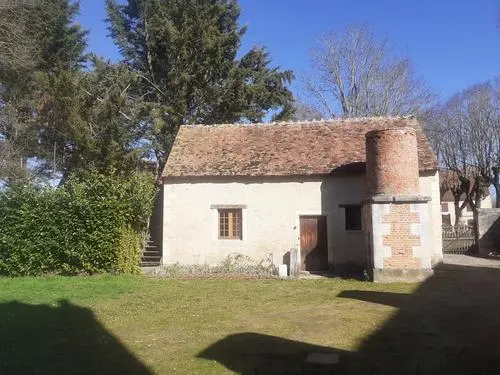 Bâtiment ancien du gîte avec tourelle ronde en brique, toiture de tuiles et escalier extérieur