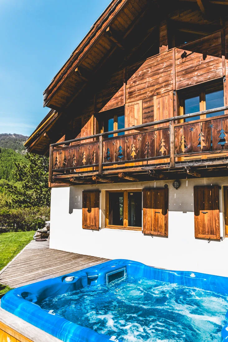 Terrasse en bois du chalet avec spa extérieur face aux volets en bois