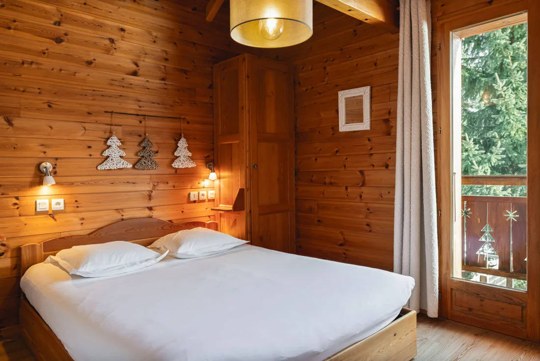 Chambre avec lit double et porte-fenêtre donnant sur le balcon en bois
