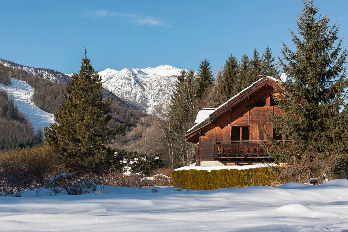 Gîte de groupe Chalet Le Serre des Oiseaux à Saint-Chaffrey — Chalet Le Serre des Oiseaux vu de l'extérieur sous la neige avec les montagnes de Serre Chevalier en arrière-plan, capacité 15 personnes