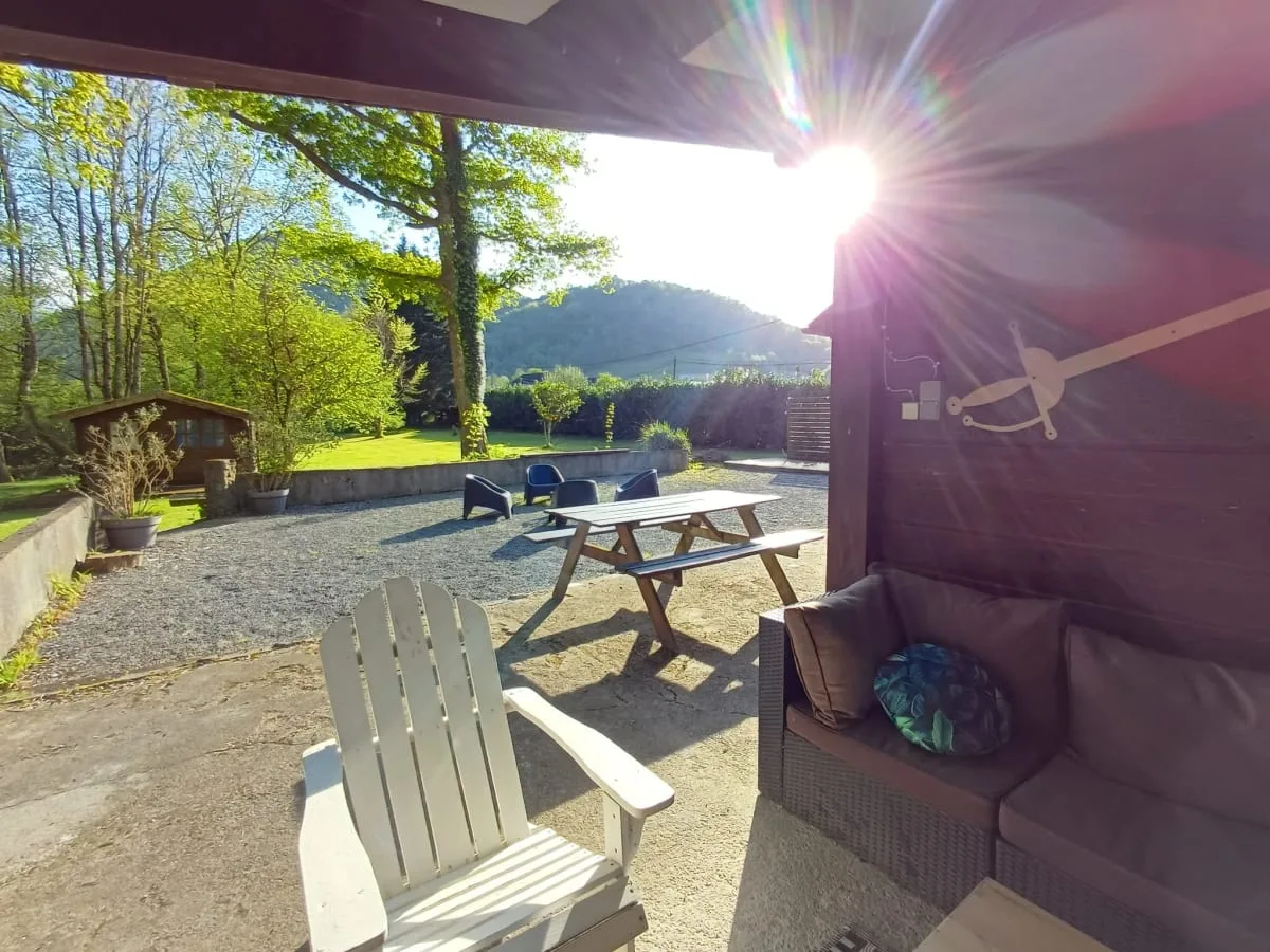 Terrasse couverte du gîte avec salon extérieur, table de pique-nique en bois et vue sur les montagnes basques
