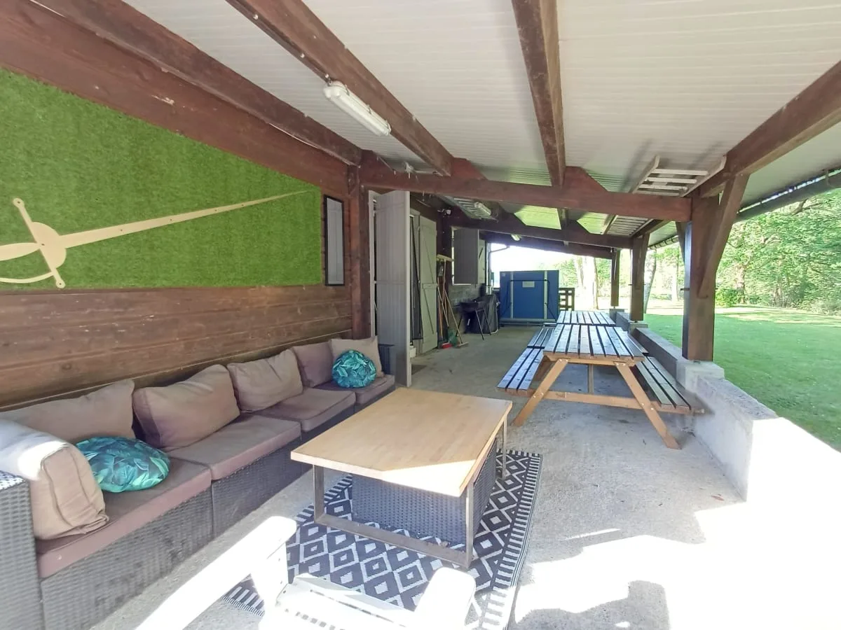 Coin salon extérieur sous la terrasse avec canapés, décoration à l'épée façon mousquetaires
