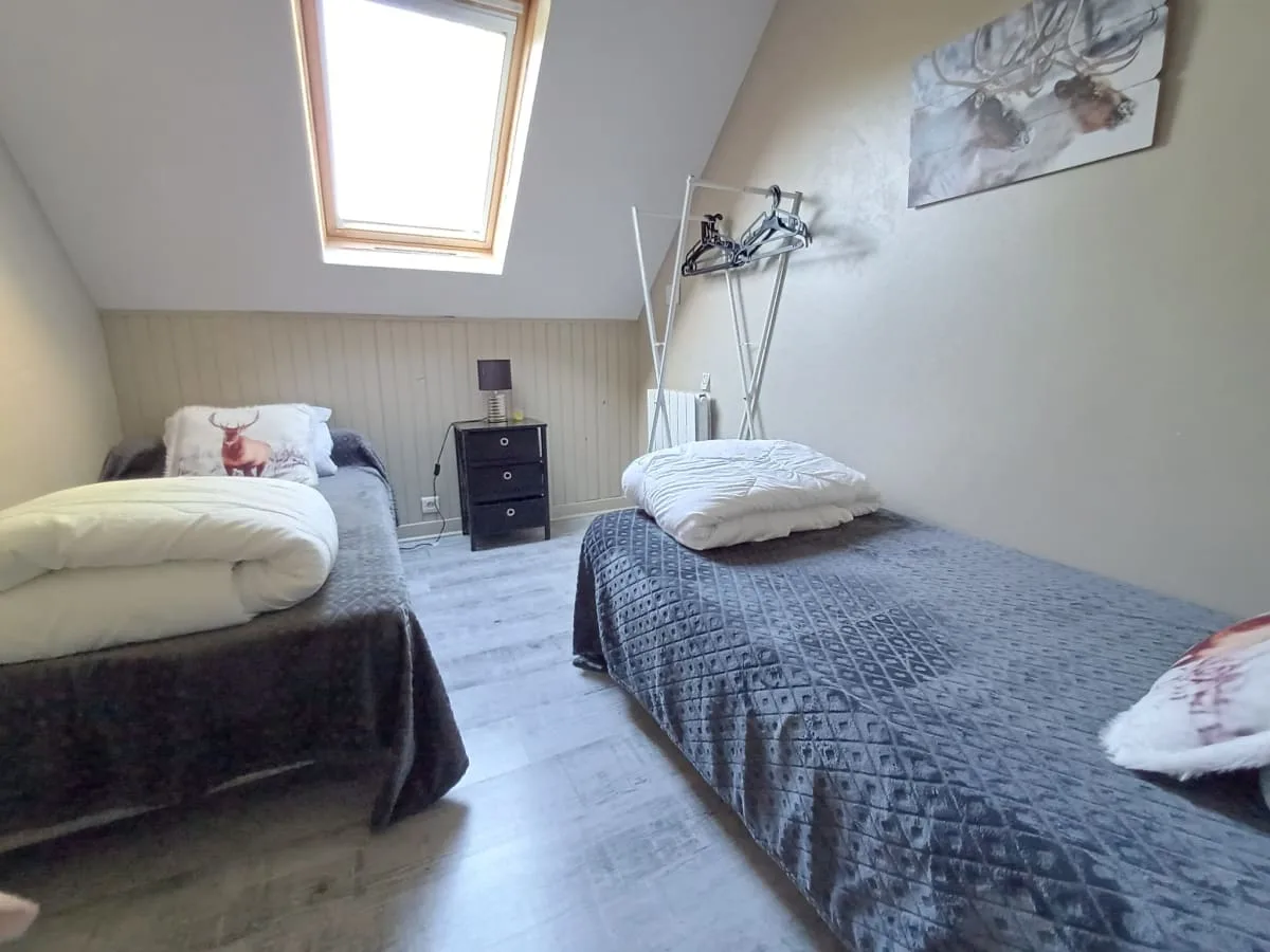 Chambre à lits jumeaux sous les combles avec velux et linge de lit motif cerf