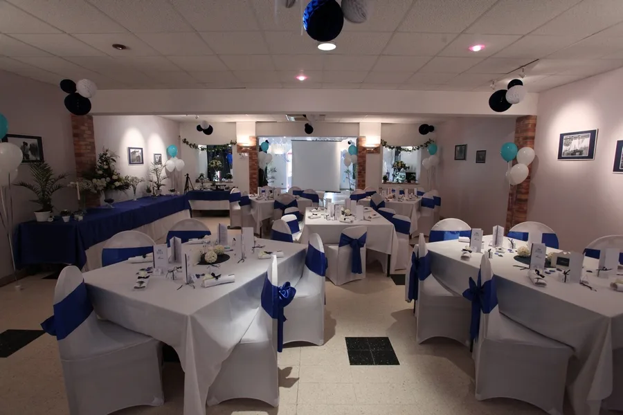 Salle de réception dressée avec nappes et housses de chaises bleu et blanc