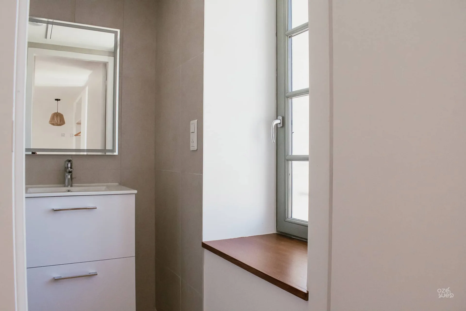 Salle d'eau moderne avec vasque blanche et grande fenêtre lumineuse