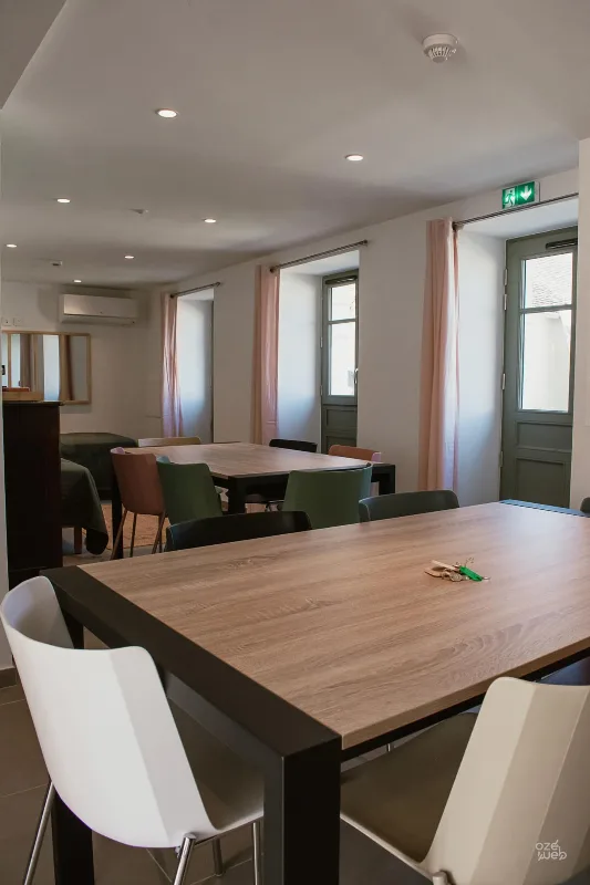 Salle à manger et coin salon du gîte Le Chêne Vert avec grandes tables en bois