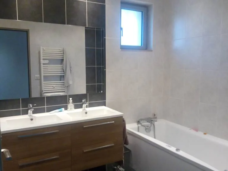 Salle de bain avec double vasque en bois, baignoire et sèche-serviettes