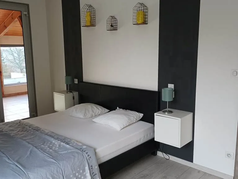 Chambre avec lit double, chevets suspendus et couronne décorative au mur