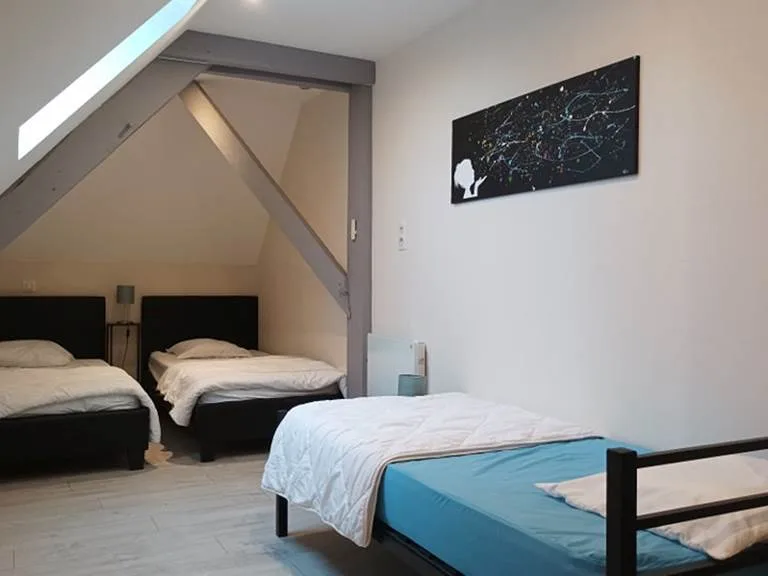 Chambre mansardée avec trois lits simples sous les combles, idéale pour les enfants