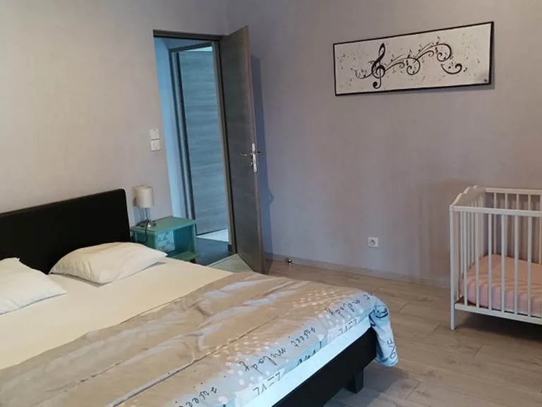 Chambre avec lit double et lit bébé, ambiance douce et lumineuse