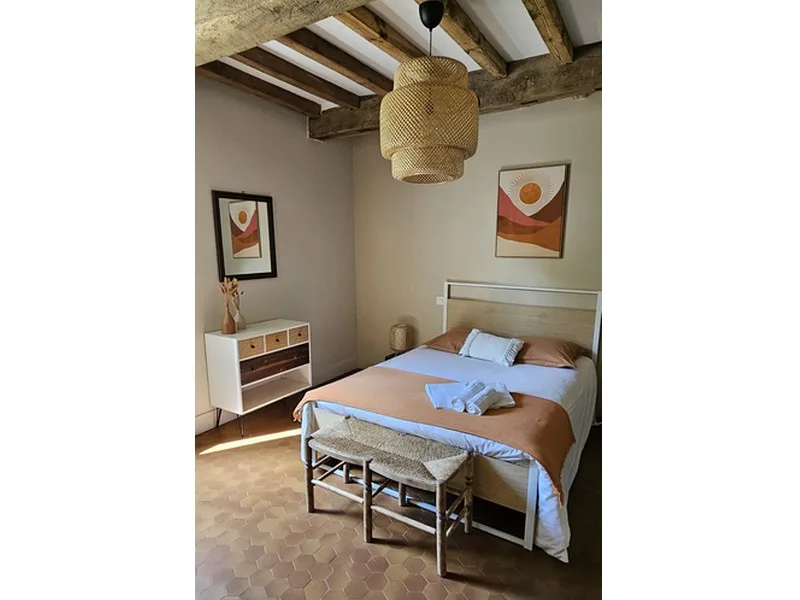 Chambre aux tons beiges avec poutres apparentes au plafond