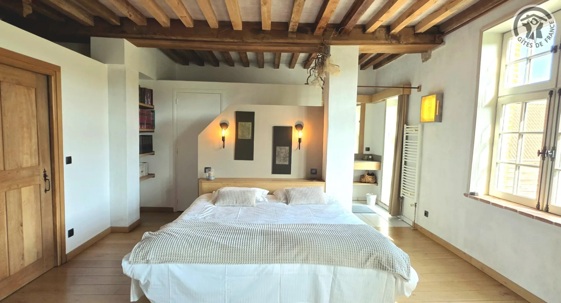 Chambre spacieuse aux poutres apparentes, lit double et mobilier en bois clair