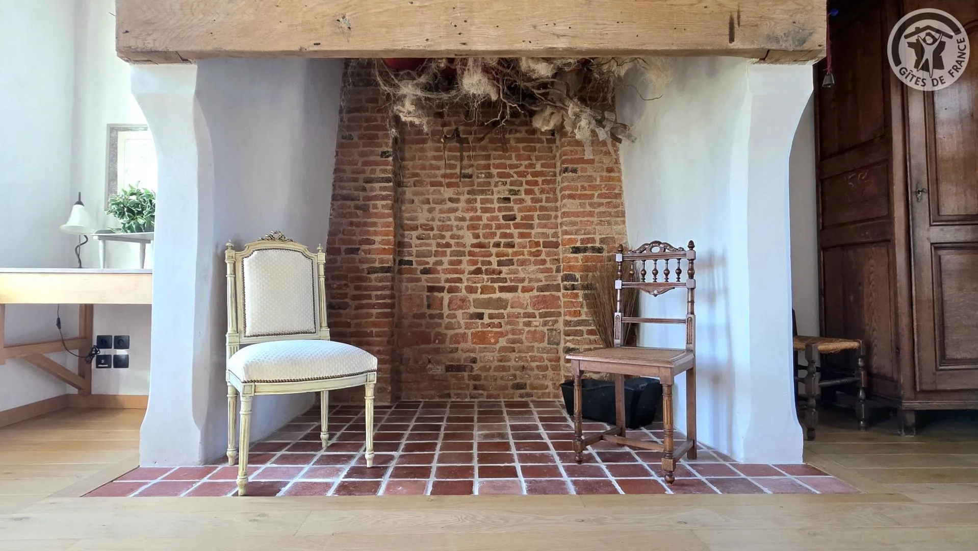 Ancienne cheminée en briques apparentes avec chaises anciennes de part et d'autre