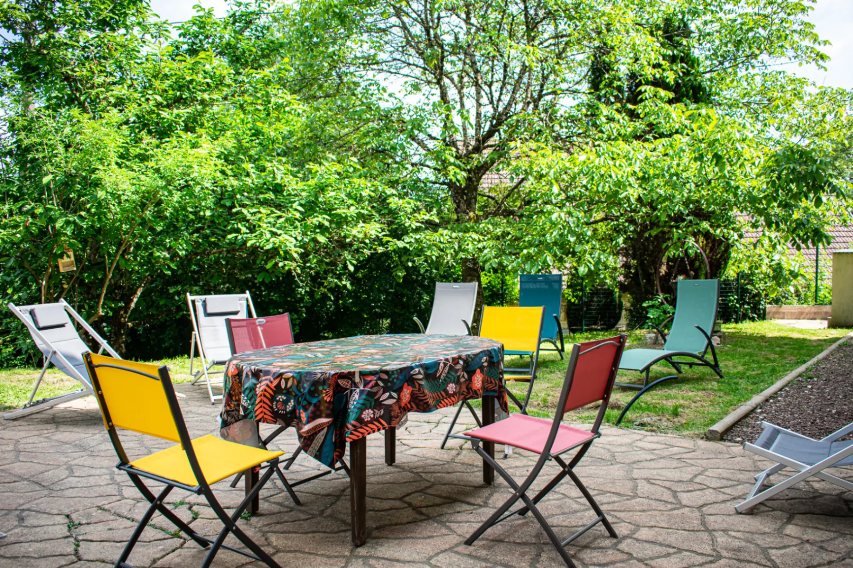 Jardin ombragé avec transats colorés autour d'une table sur la terrasse