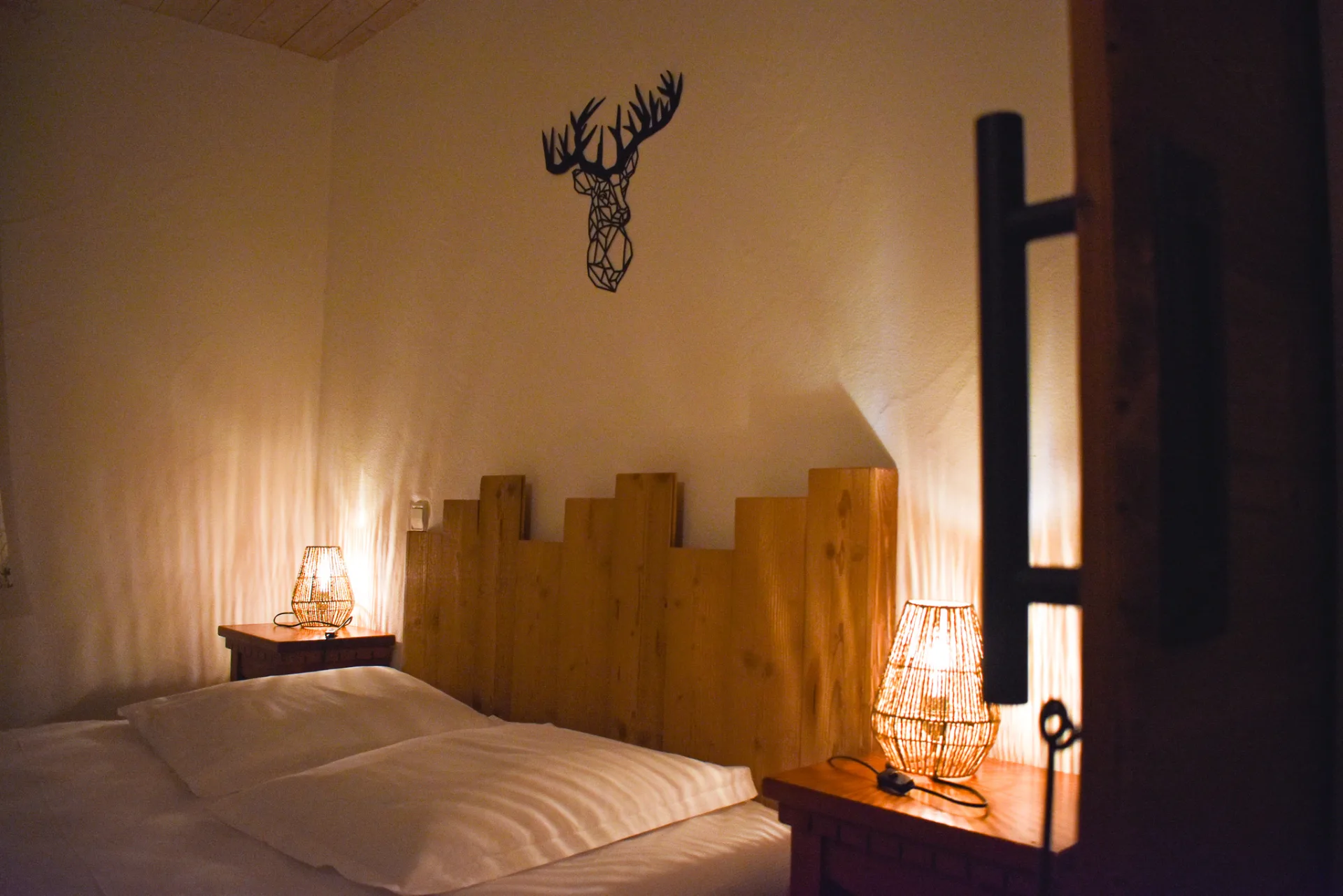Chambre cosy avec tête de lit en bois et décor cerf géométrique au mur