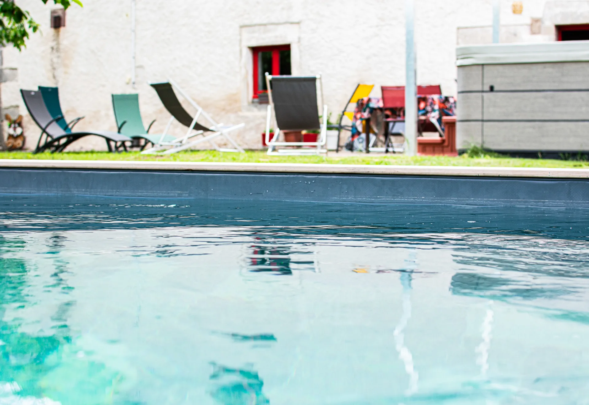 Le Gîte des Ronchots vu de la piscine extérieure et de la façade en pierre