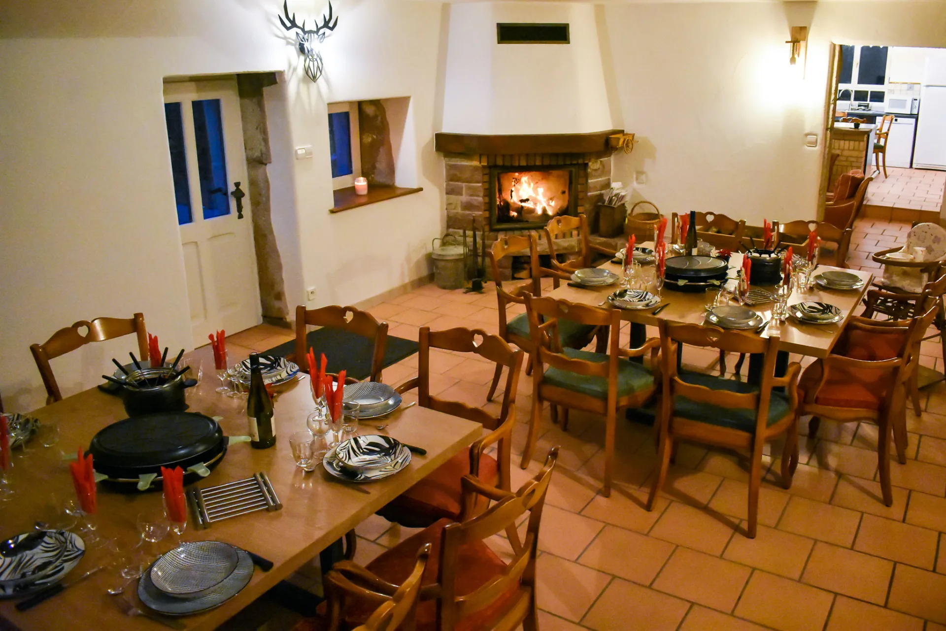 Grande salle à manger dressée pour une raclette de groupe devant la cheminée