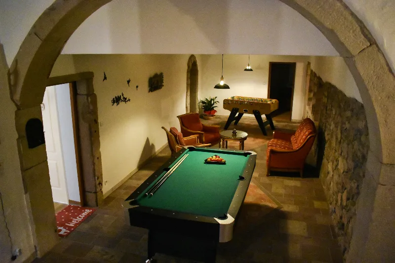Salle de billard voûtée en pierre avec fauteuils et babyfoot