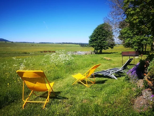 Transats jaunes installés dans le jardin face aux prés