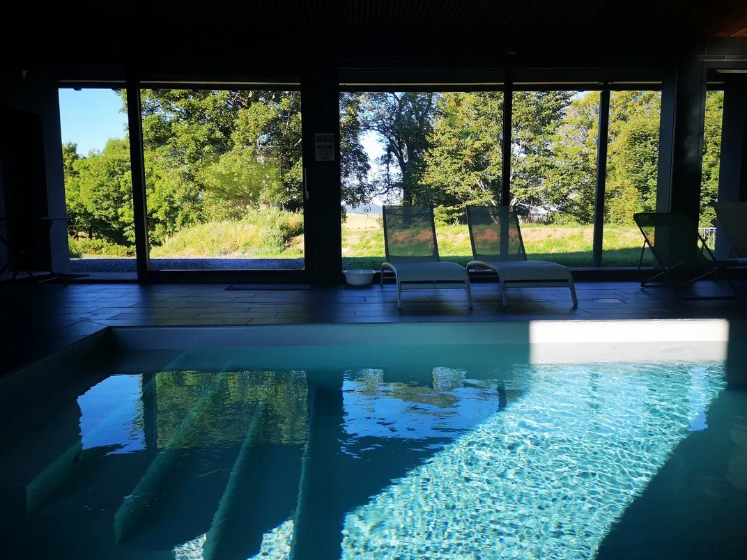 Piscine intérieure chauffée avec vue sur la campagne environnante en été