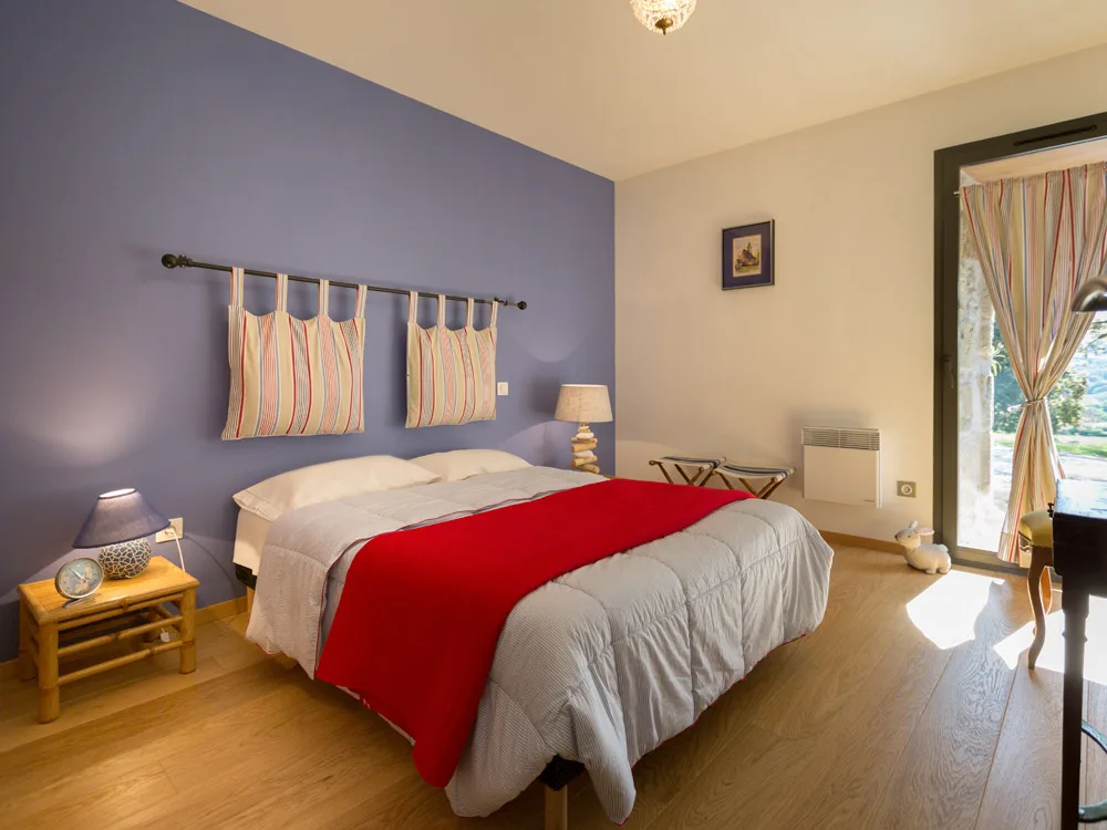 Chambre au mur bleu avec plaid rouge sur le lit