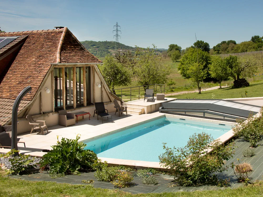 Piscine chauffée et terrasse avec transats devant la véranda