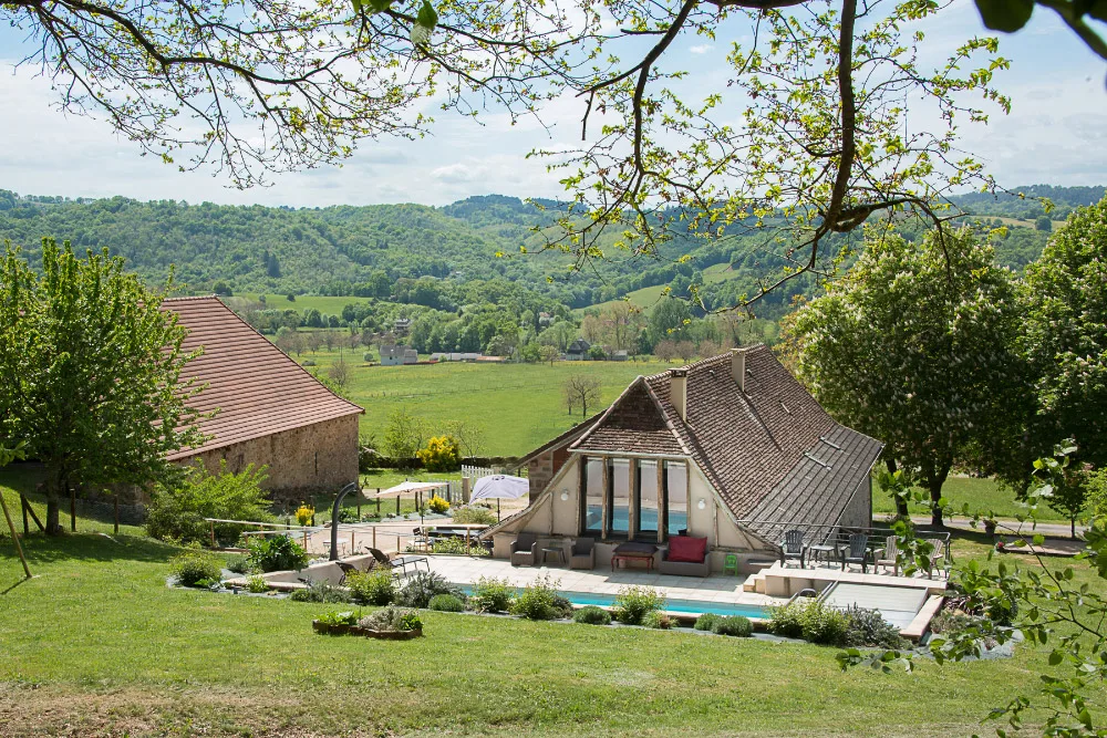 Vue d'ensemble du gîte et de la piscine dominant la vallée