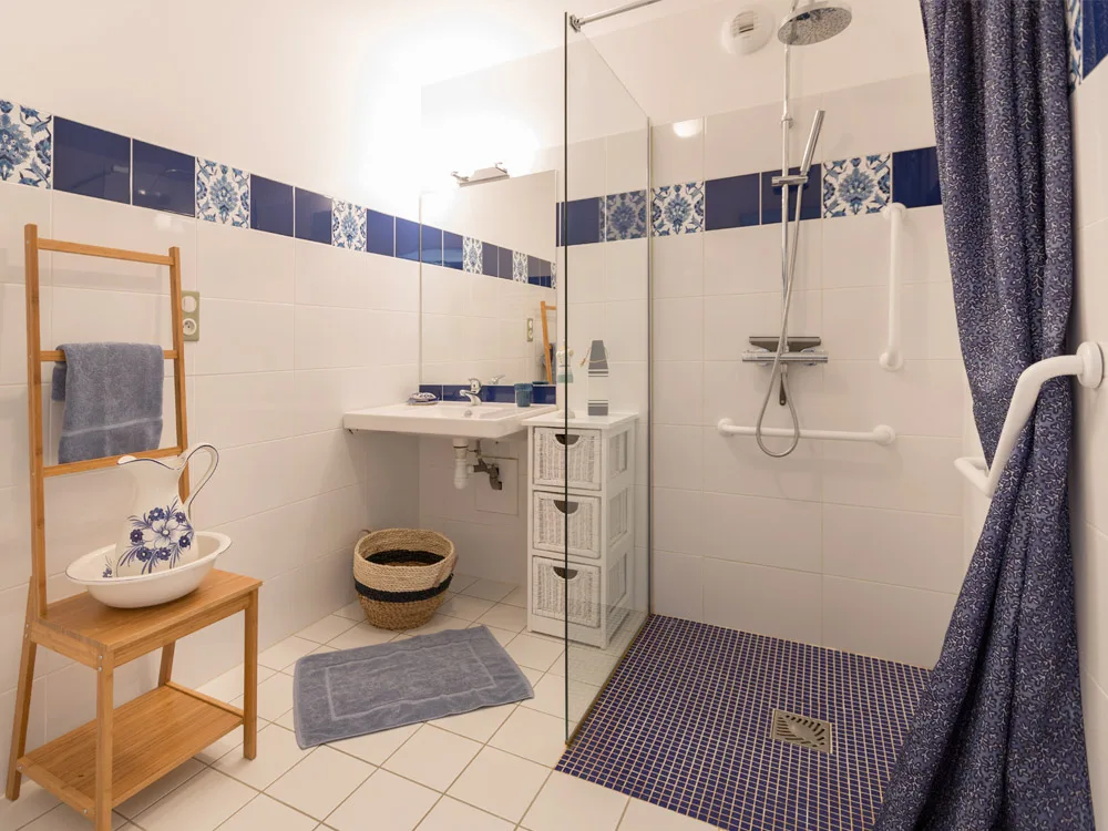 Salle d'eau PMR au carrelage bleu et blanc, douche à l'italienne
