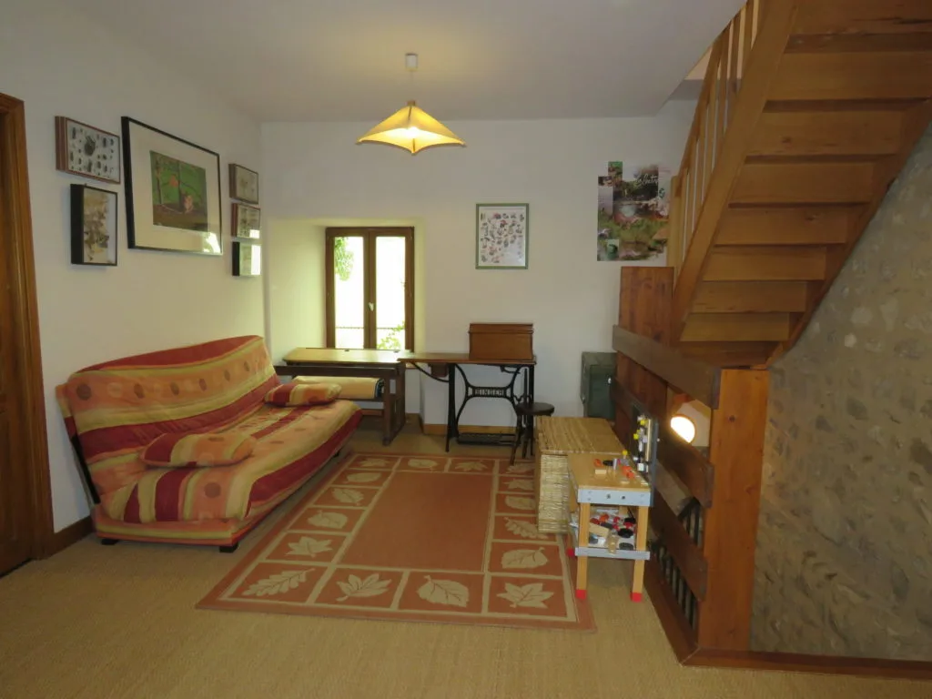Coin salon sous l'escalier en bois avec canapé convertible et jeux pour enfants