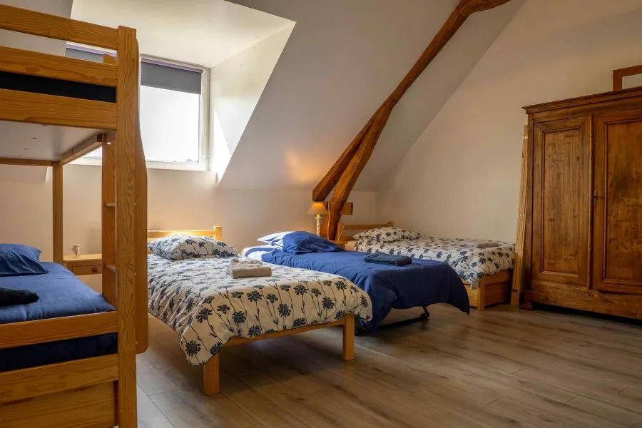 Chambre mansardée avec deux lits jumeaux fleuris sous poutres apparentes