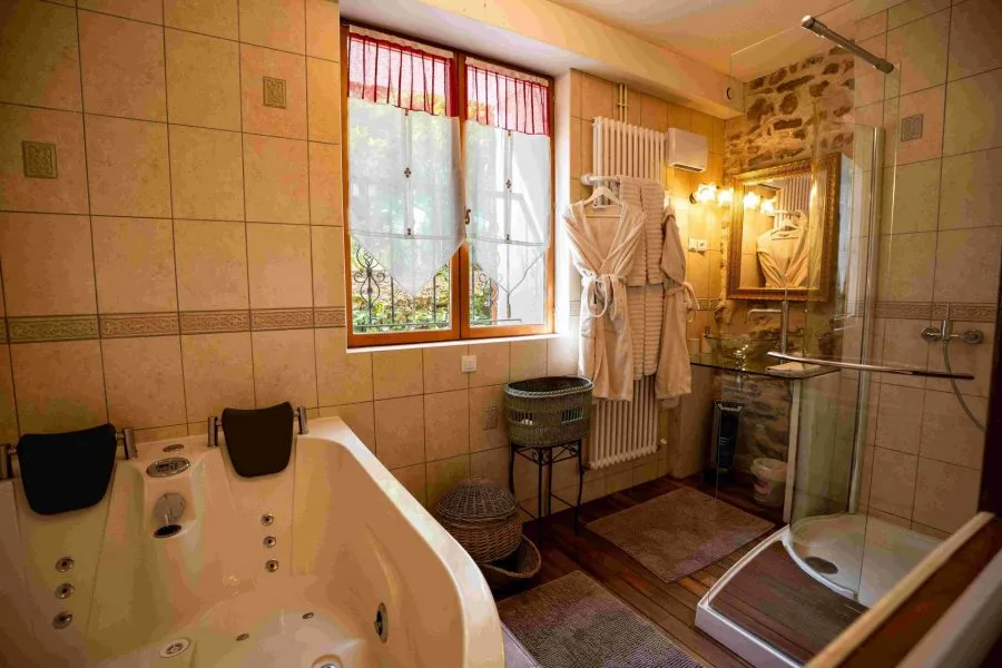 Salle de bain avec baignoire balnéo, douche à l'italienne et pierres apparentes