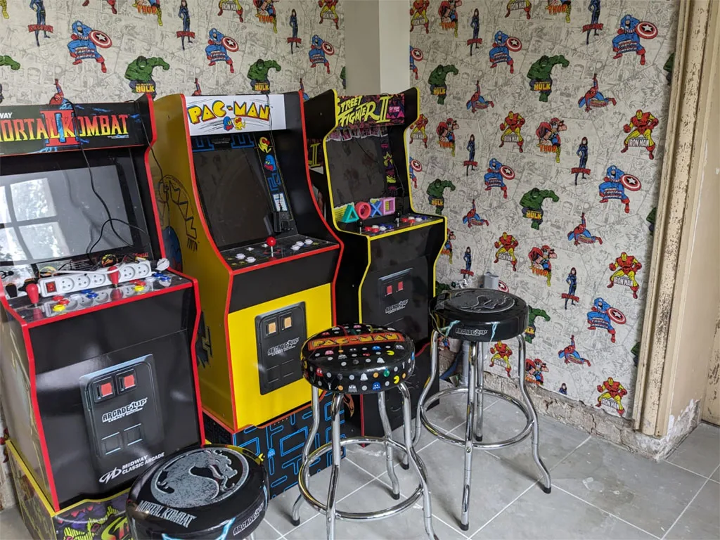Salle de jeux vidéo à thème super-héros avec bornes d'arcade et papier peint illustré
